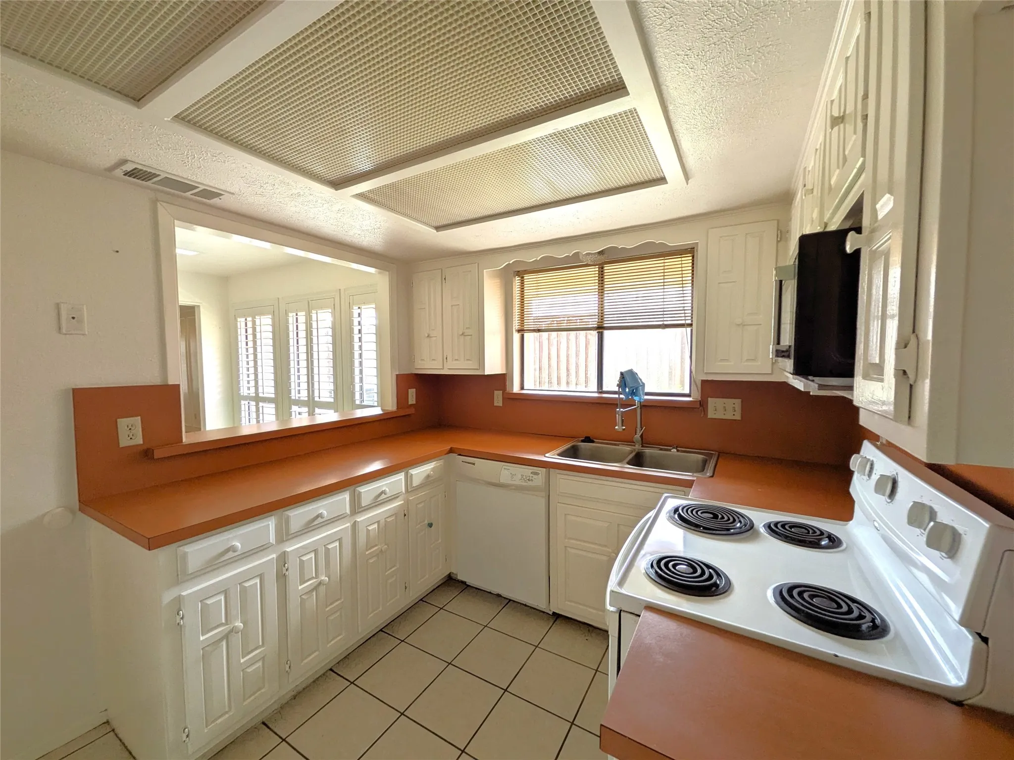 Kitchen featuring white cabinetry, solid surface countertops, double basin sink, and a four-burner electric range