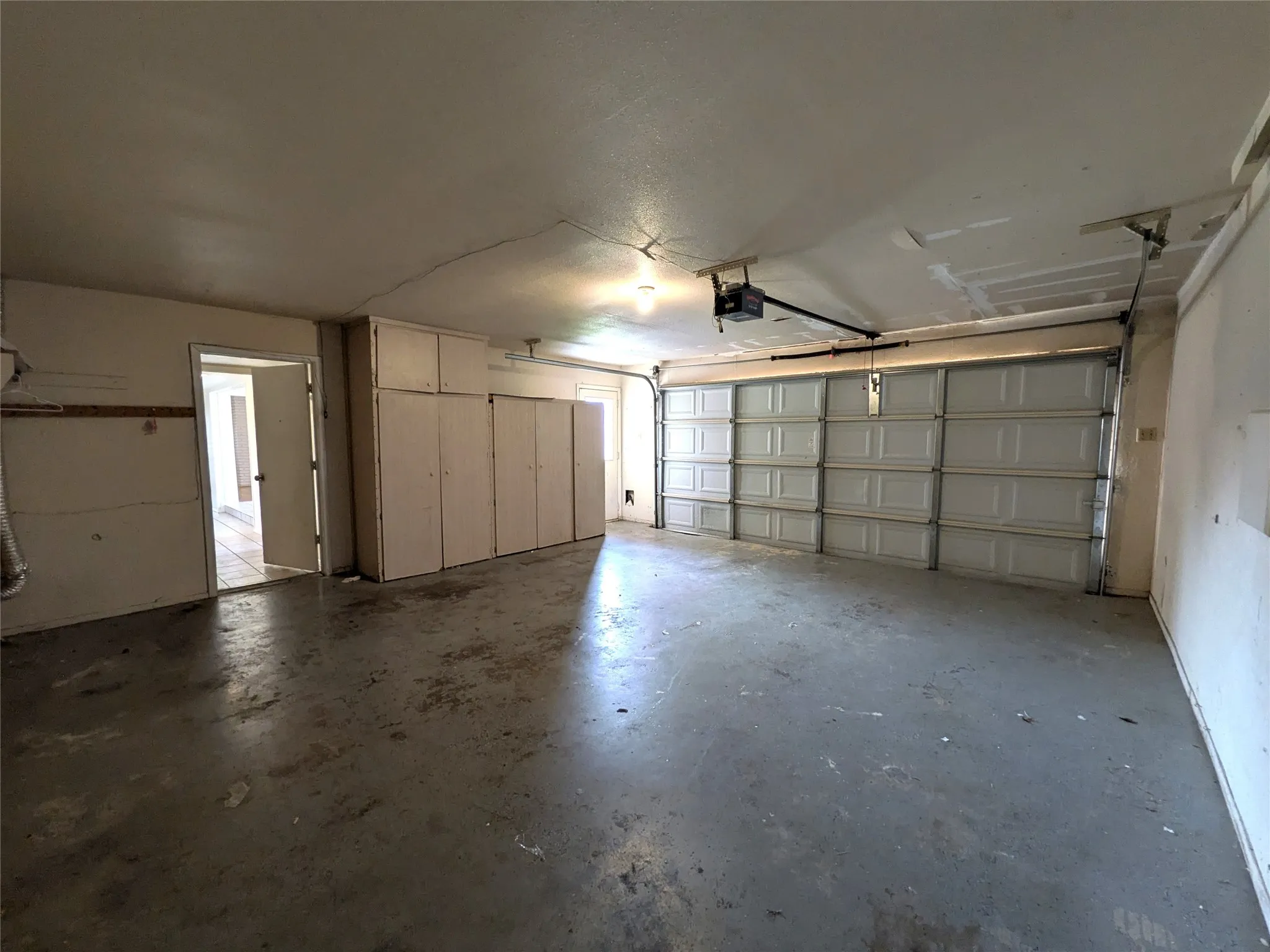 Spacious garage featuring a paneled overhead door, concrete flooring, and extensive built-in cabinetry