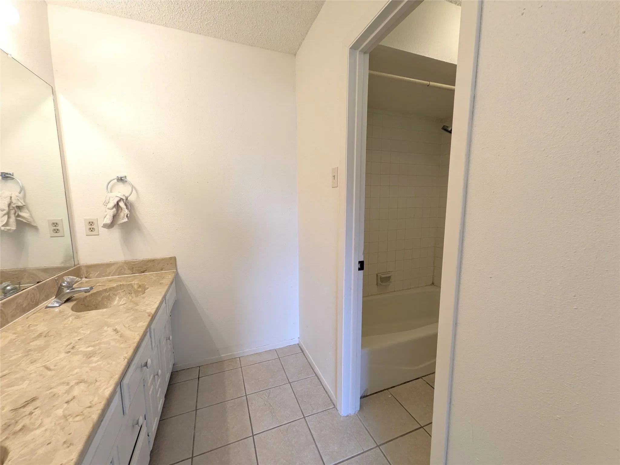 Bathroom featuring a double vanity with a light-toned stone countertop, dual undermount sinks, and white cabinetry
