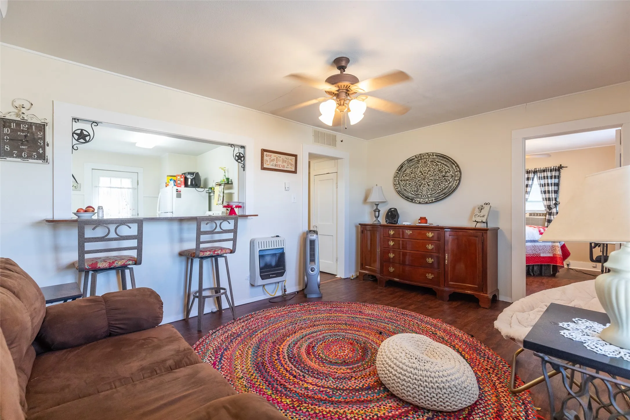 Wood-finish flooring throughout, ceiling fan with integrated lighting, and a breakfast bar with built-in shelving