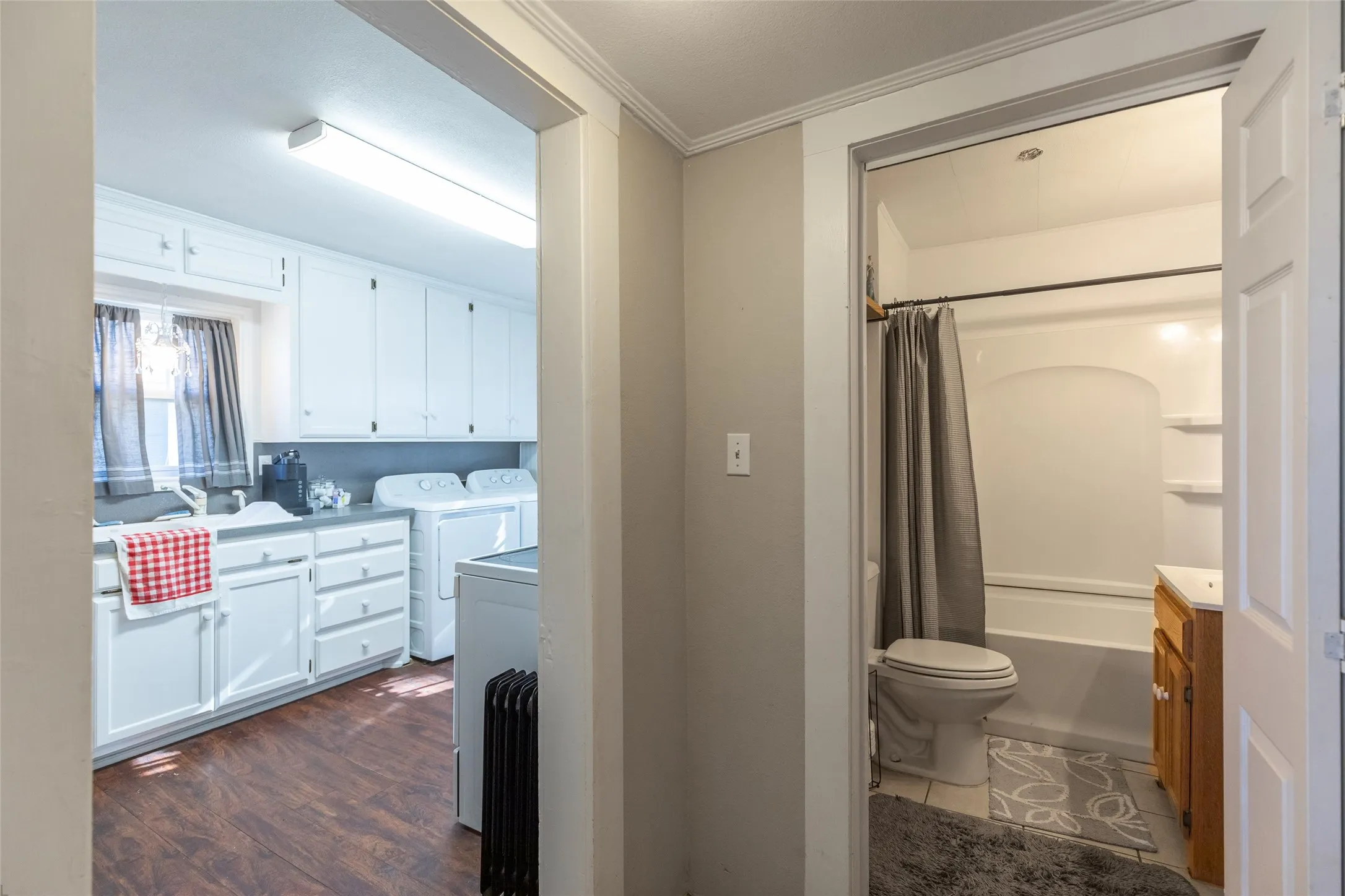 Laundry room with wood-finish flooring, white cabinetry, and an inset sink