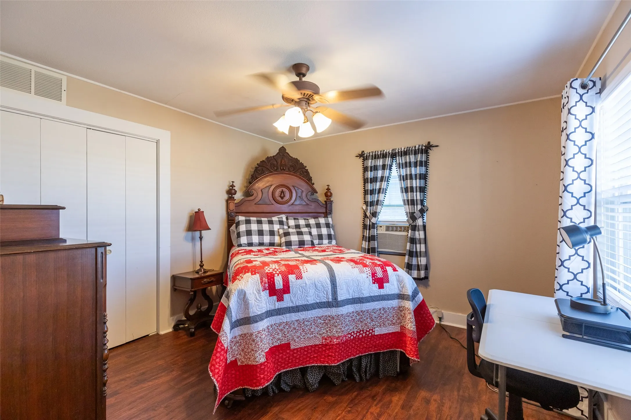 Wood-finish flooring throughout, ceiling fan with light fixture, and white bi-fold closet doors