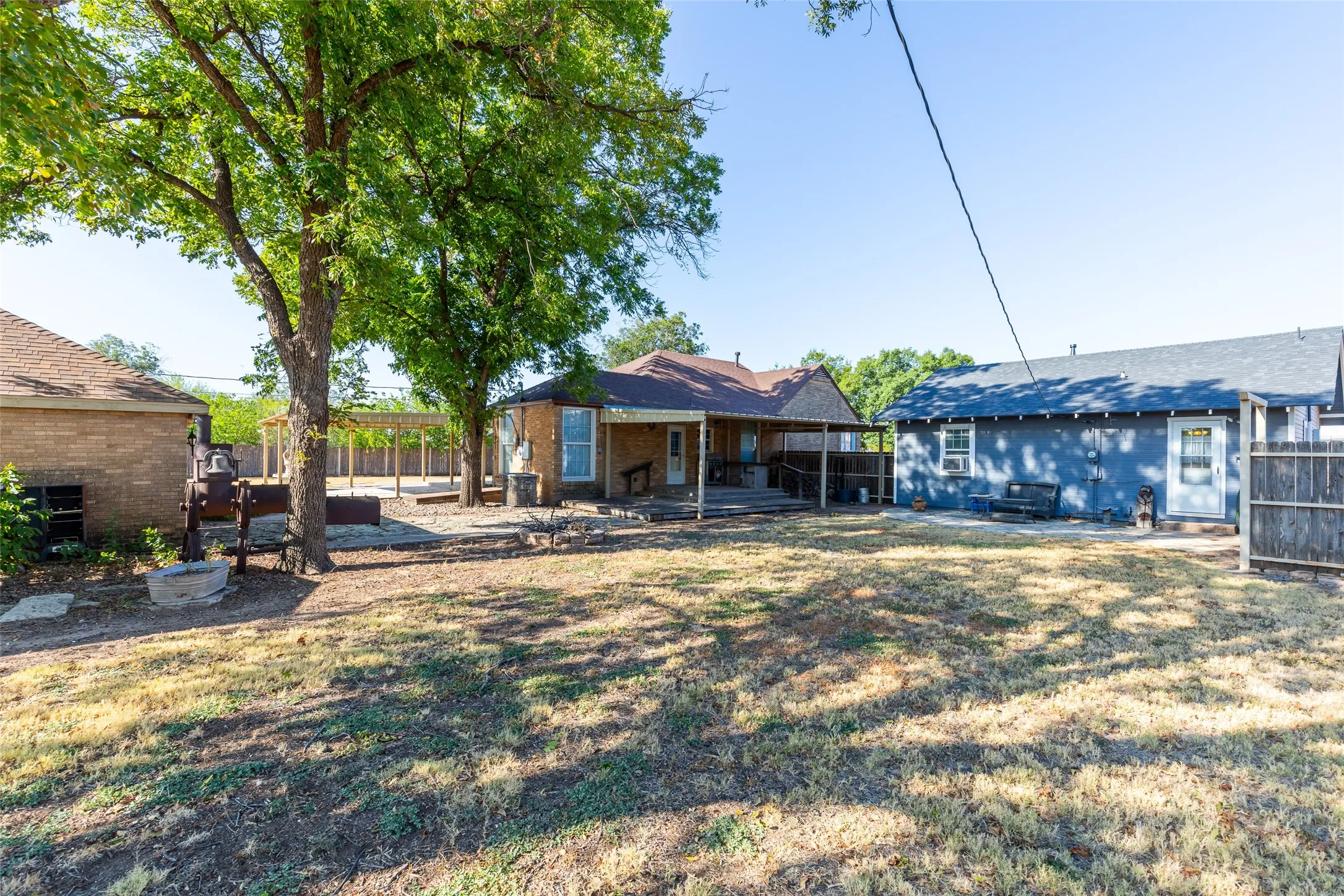 Spacious backyard featuring mature trees, a covered patio, and wood fencing