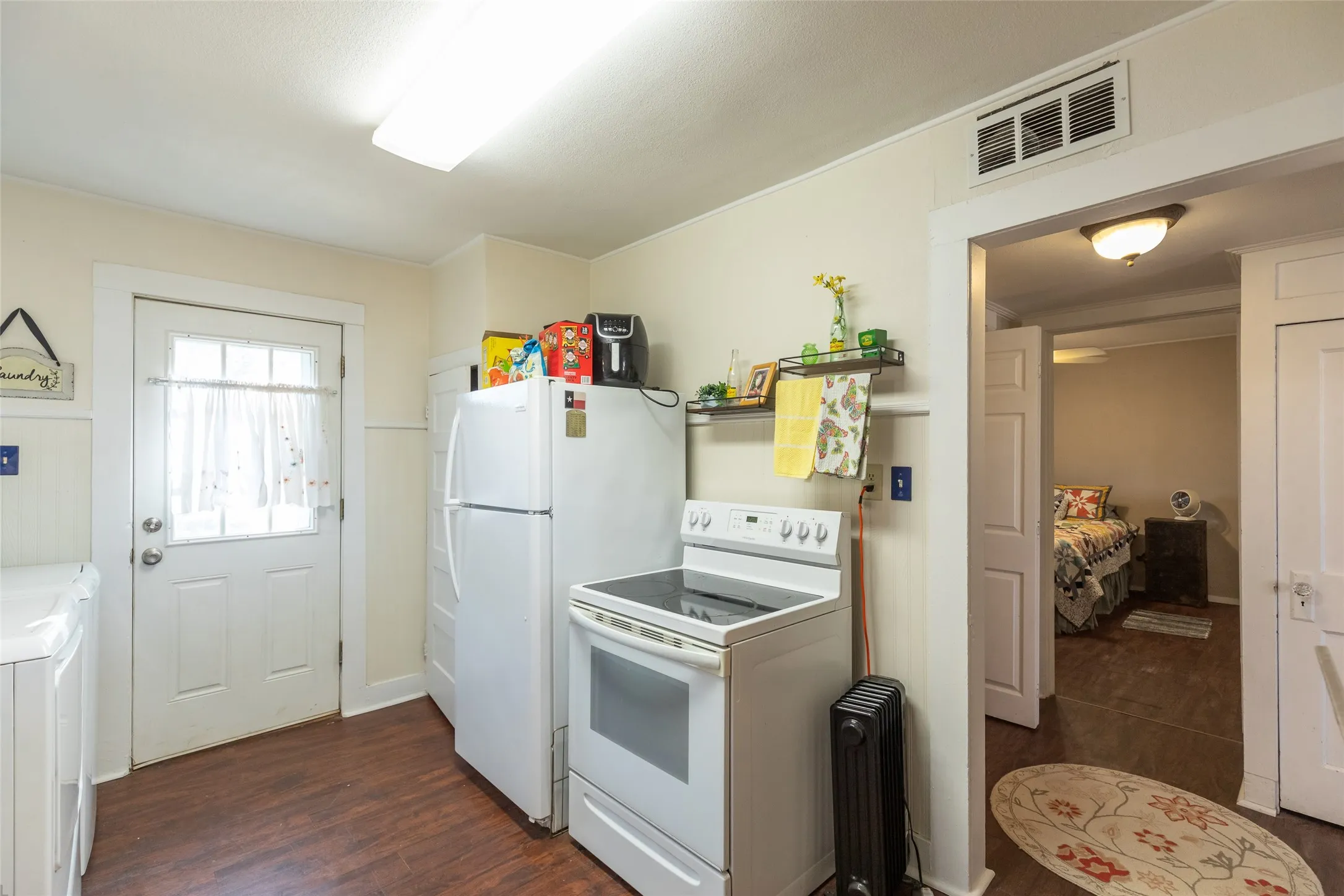 Kitchen featuring wood-finish flooring, white appliances, and a solid exterior door with a window pane