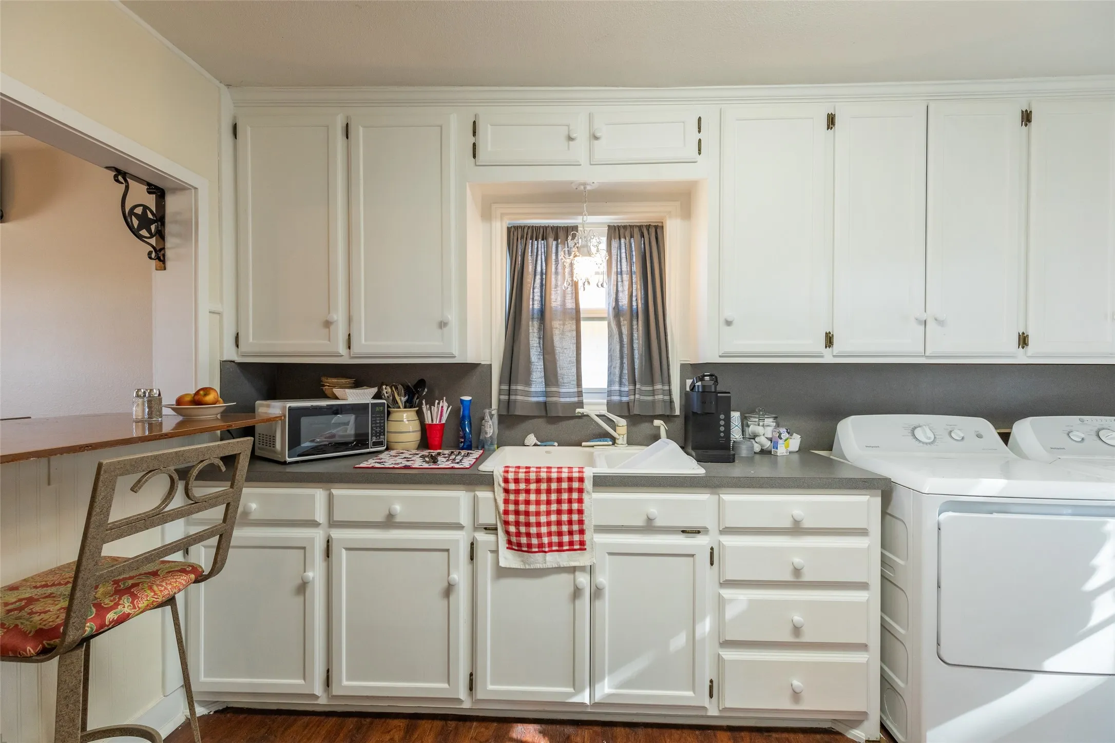 White cabinetry, wood-finish flooring, built-in sink, and countertop space