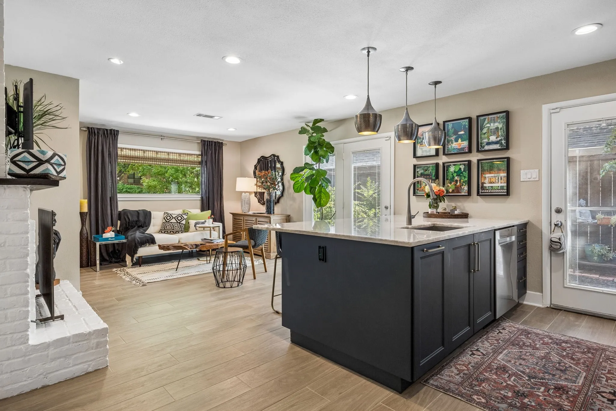 Open-concept living space with wood-finish flooring, a white brick see through fireplace, and recessed lighting