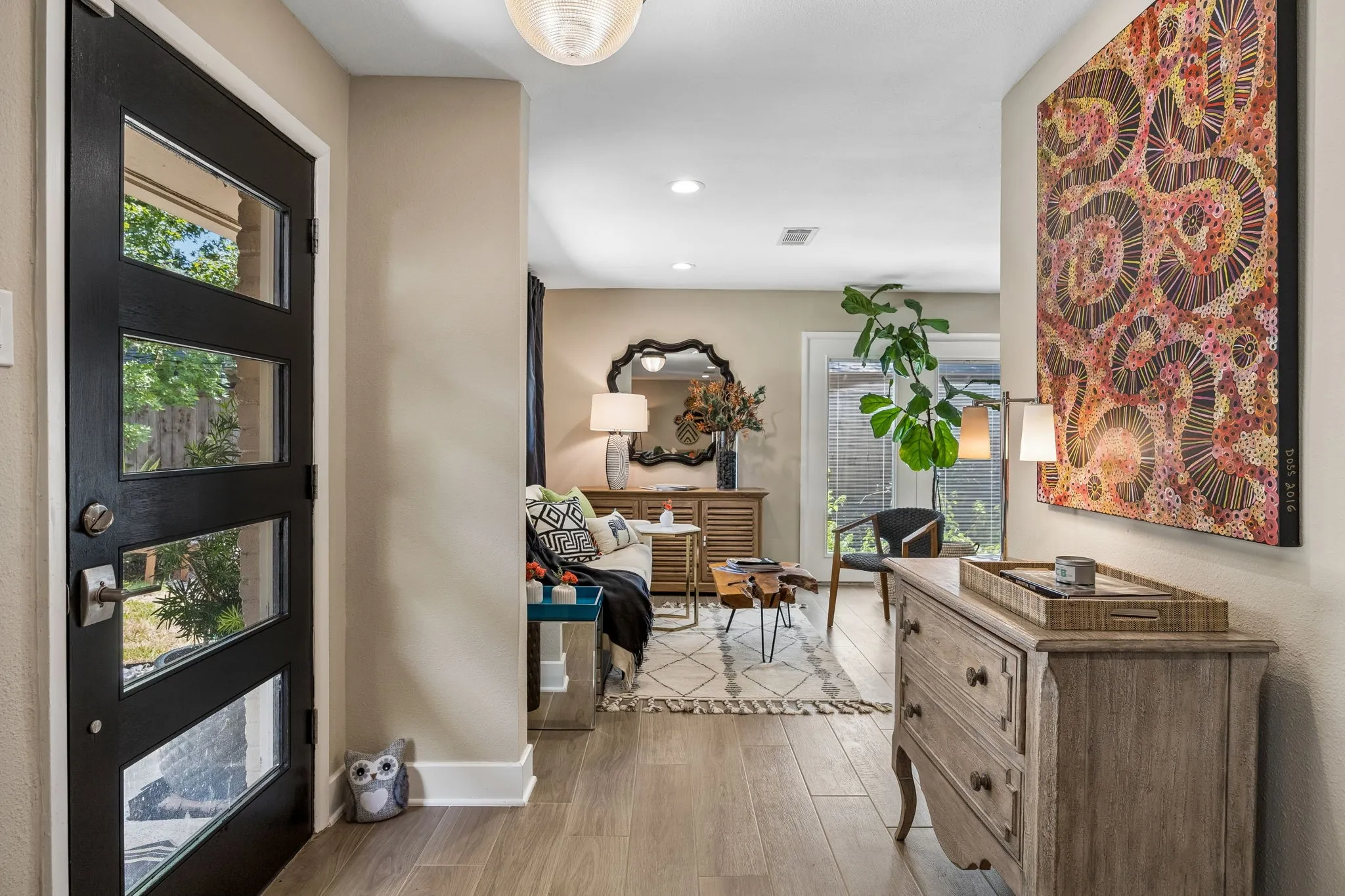 Modern entry door with multiple glass panes, light wood-finish flooring, and light neutral wall paint