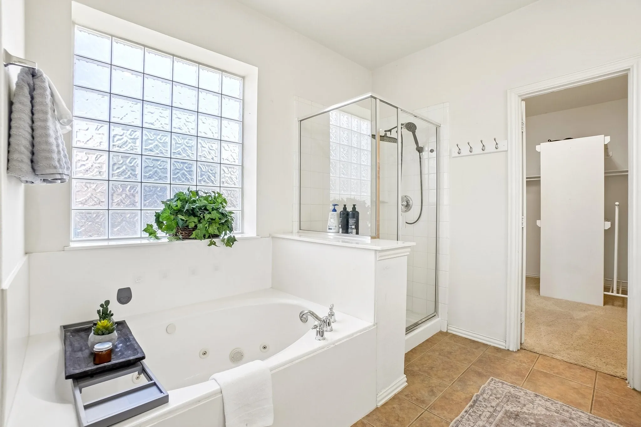 Spacious bathroom featuring a built-in jetted tub, a separate glass-enclosed shower, and a large privacy window with glass block accents