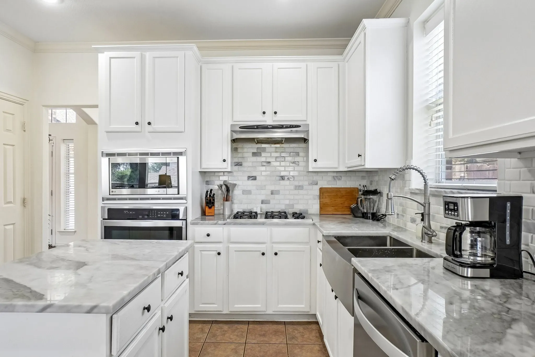 Modern kitchen featuring white shaker cabinetry, stainless steel appliances, a subway tile backsplash, and stone countertops