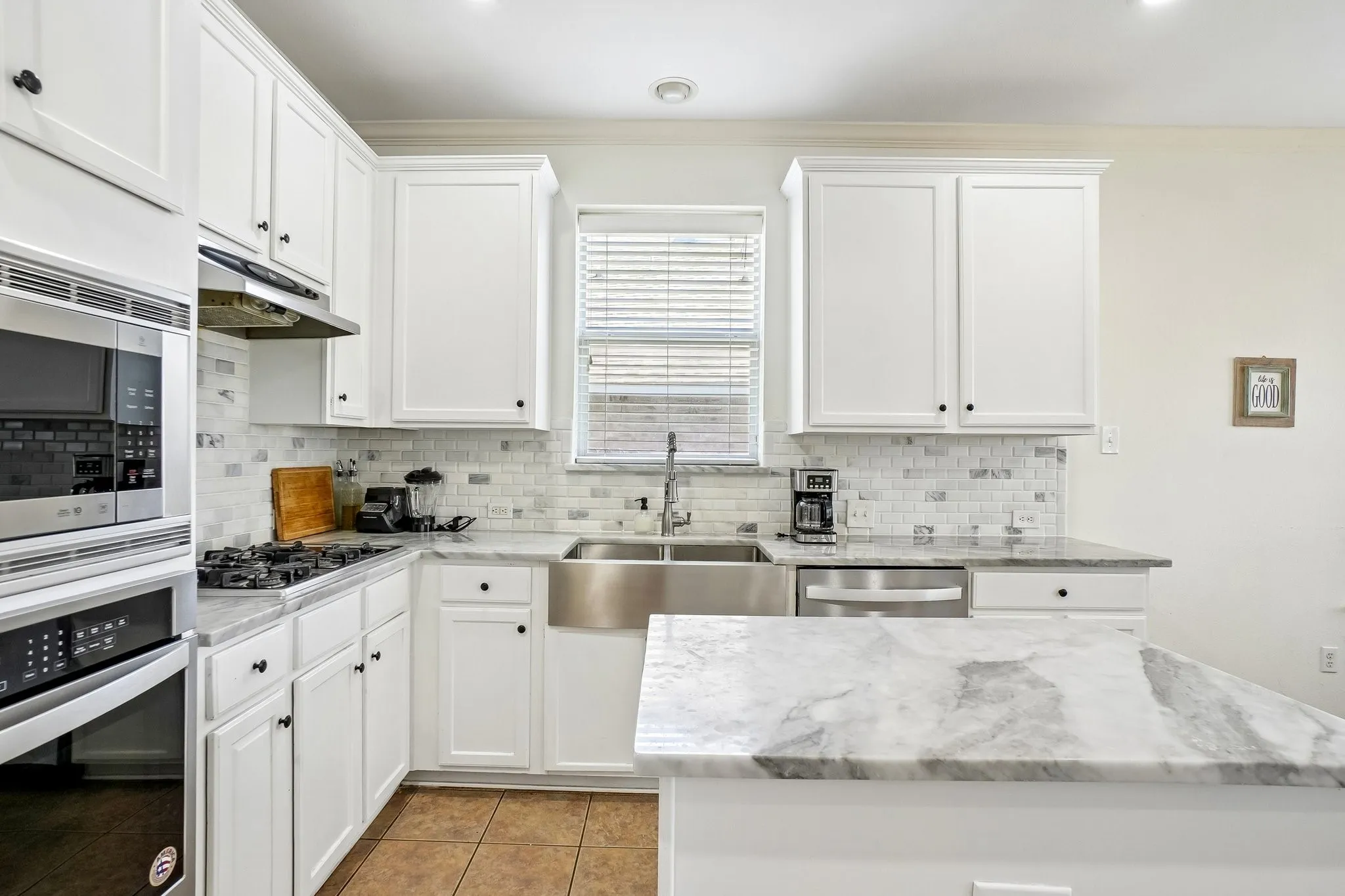 Bright kitchen featuring white cabinetry and light-toned countertops