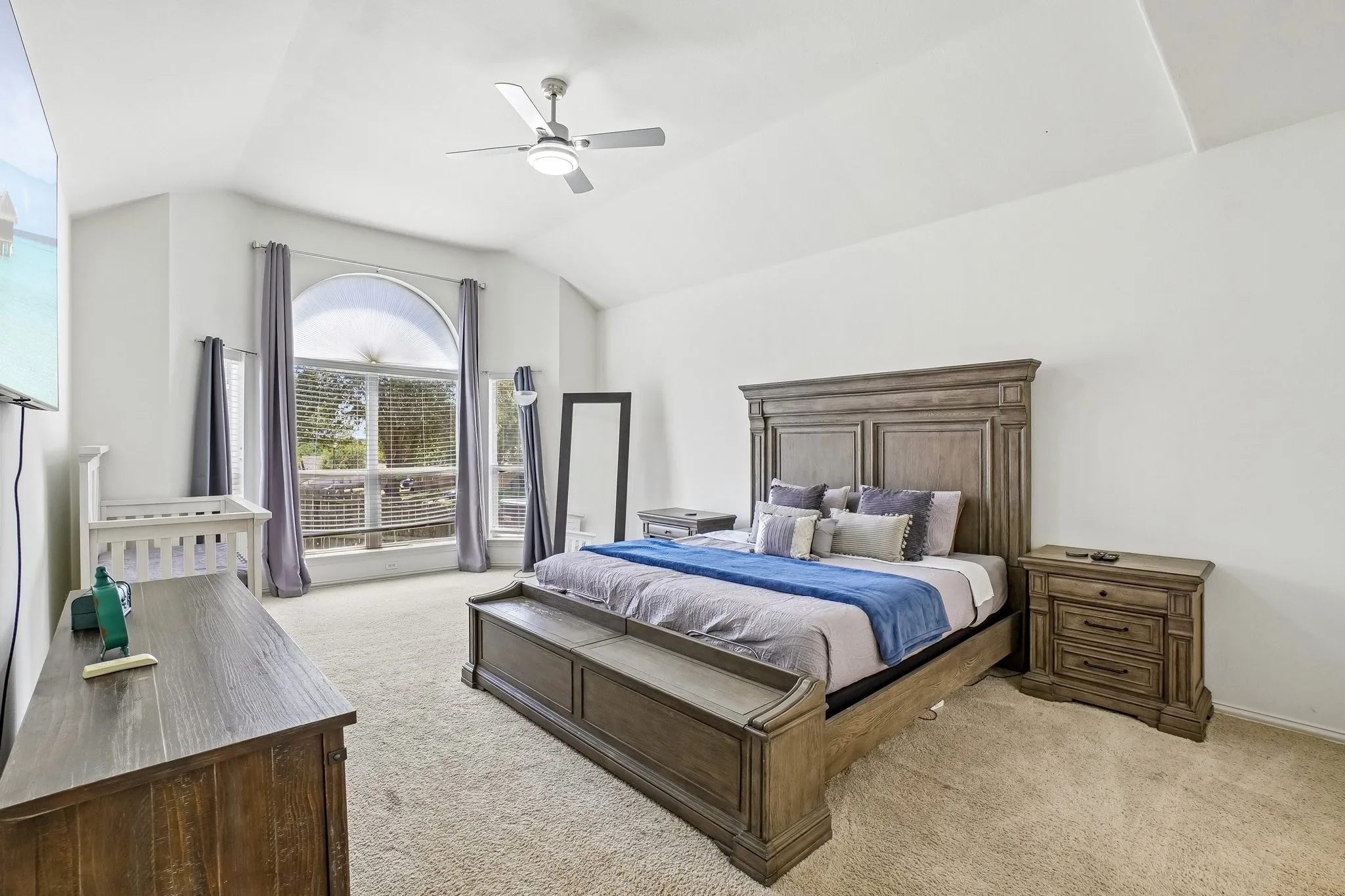 Spacious bedroom featuring a vaulted ceiling and a ceiling fan