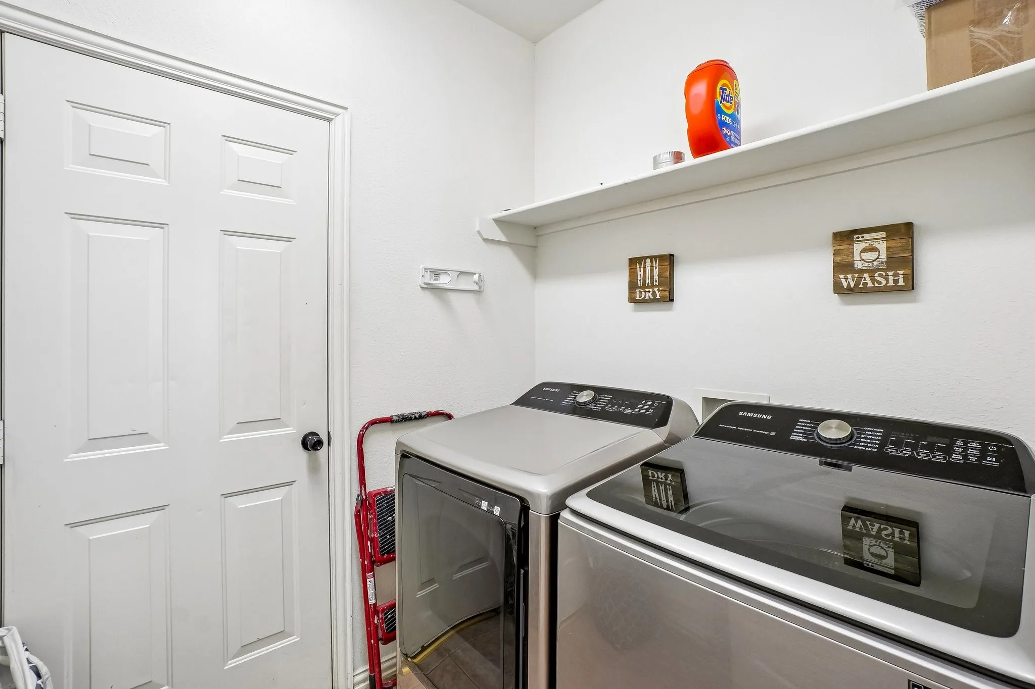 Dedicated laundry area with a five-panel interior door, overhead shelving, and light-toned walls