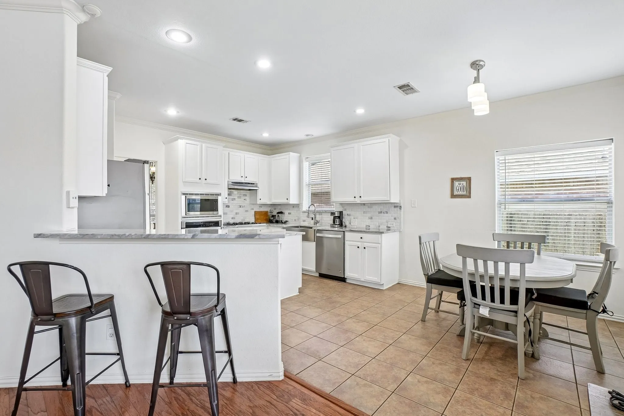 Bright kitchen featuring white cabinetry, stainless steel appliances, a tile backsplash, and recessed lighting