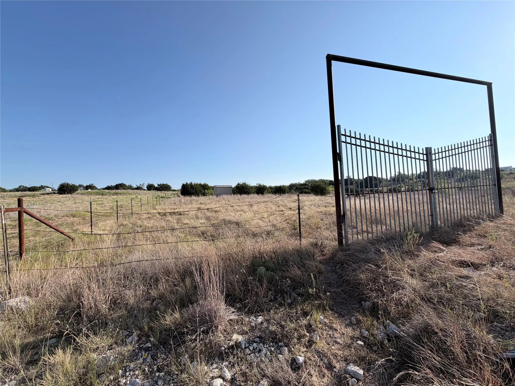 Expansive land featuring a metal fence and gate with a large metal arch