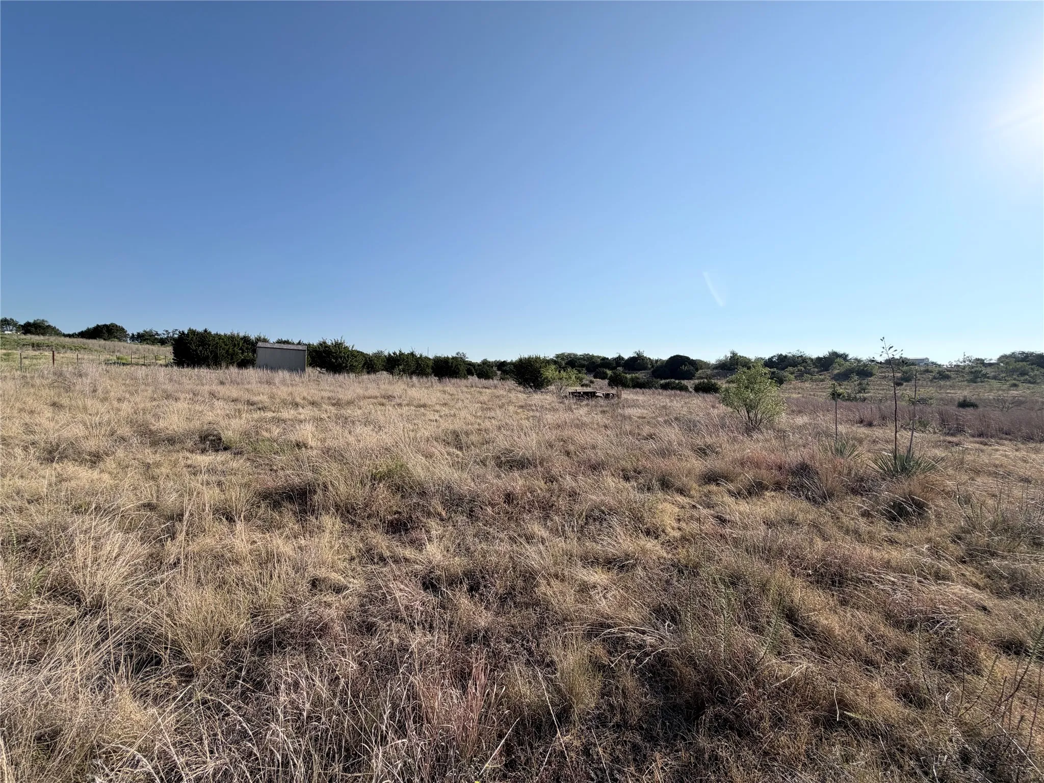 Expansive open lot featuring natural vegetation and a clear blue sky