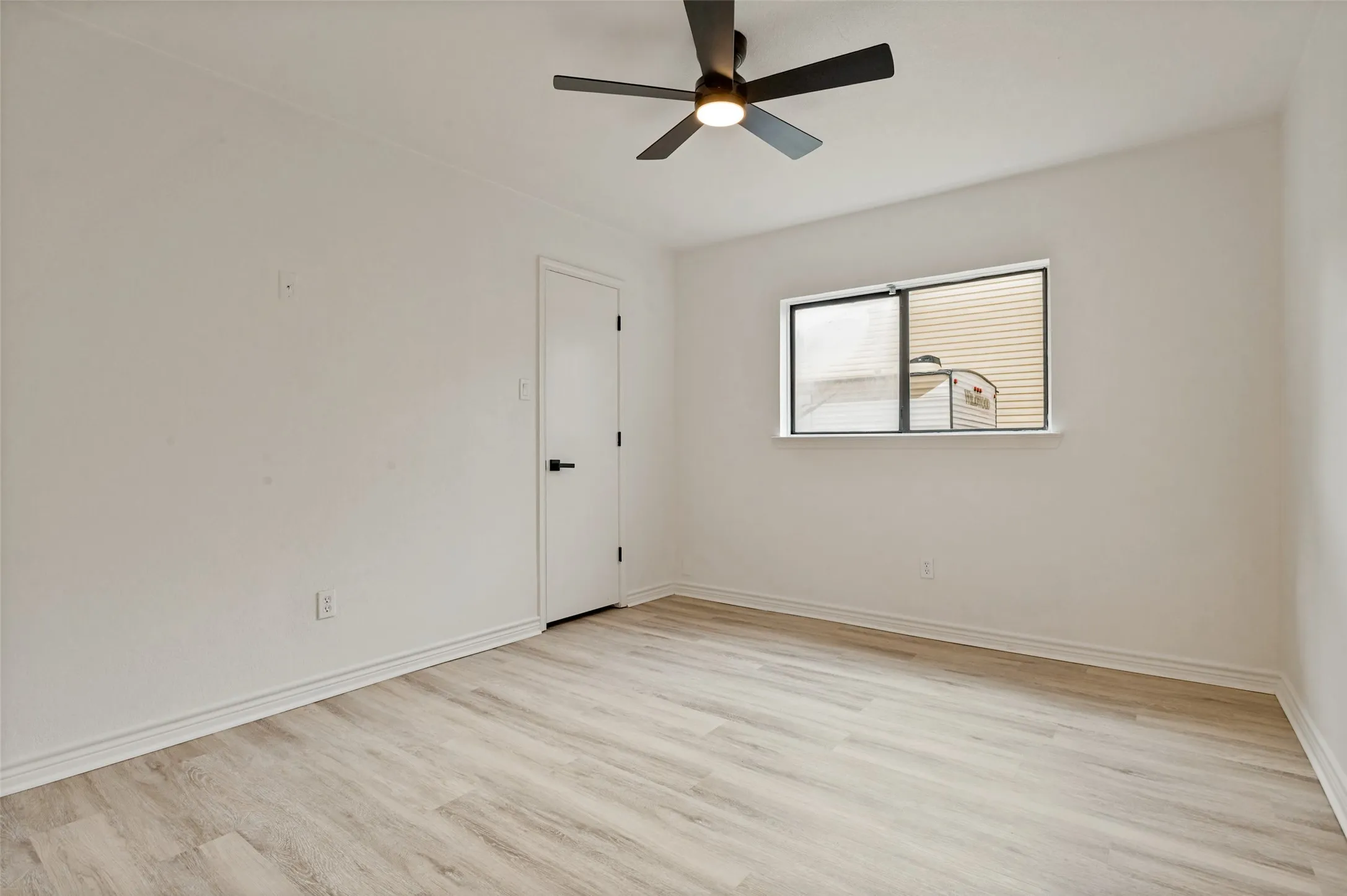 Wood-finish flooring, white walls, and a ceiling fan with integrated lighting
