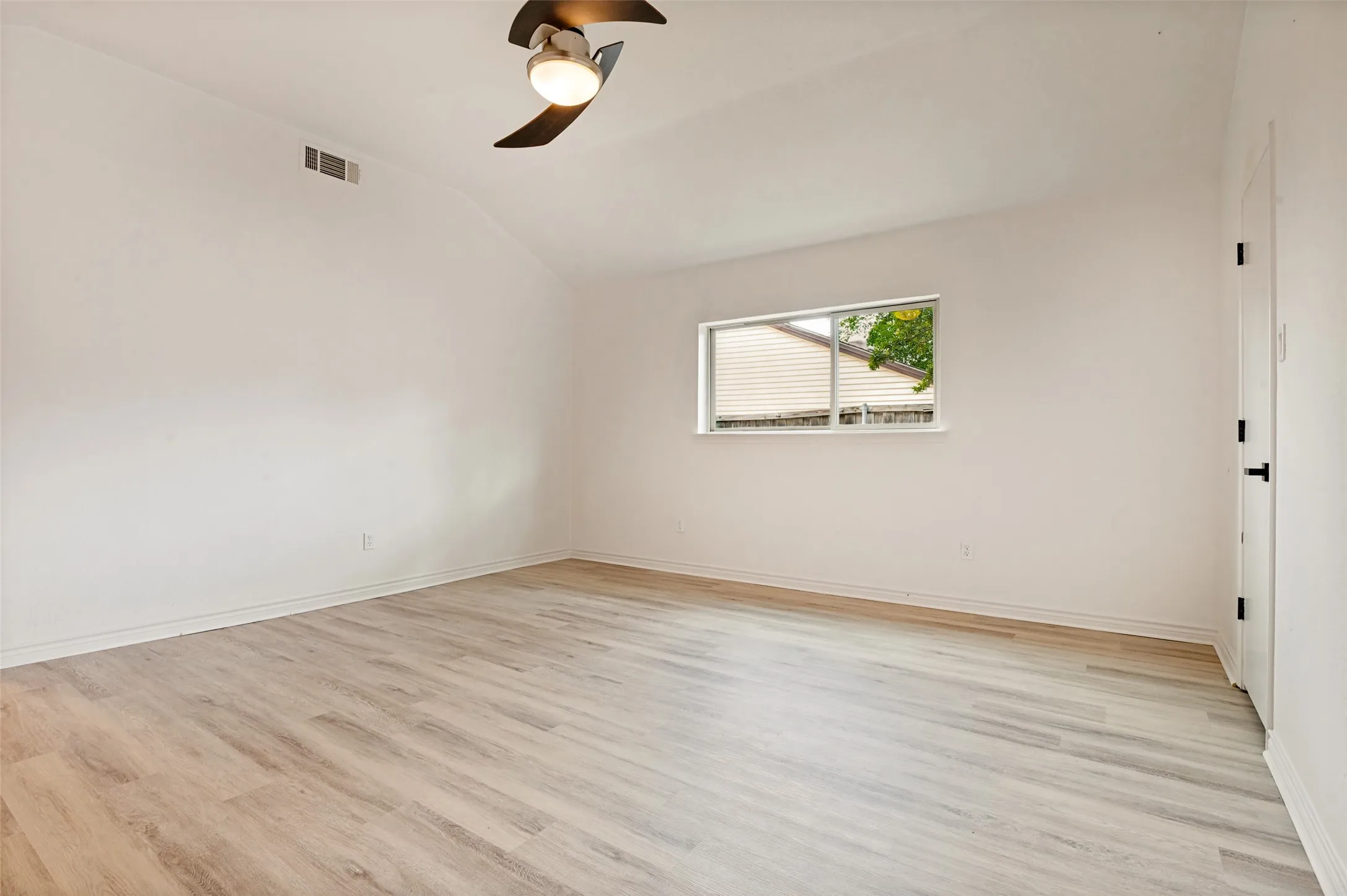 Vaulted ceiling with a ceiling fan, light wood-finish flooring, white walls, and a window with blinds