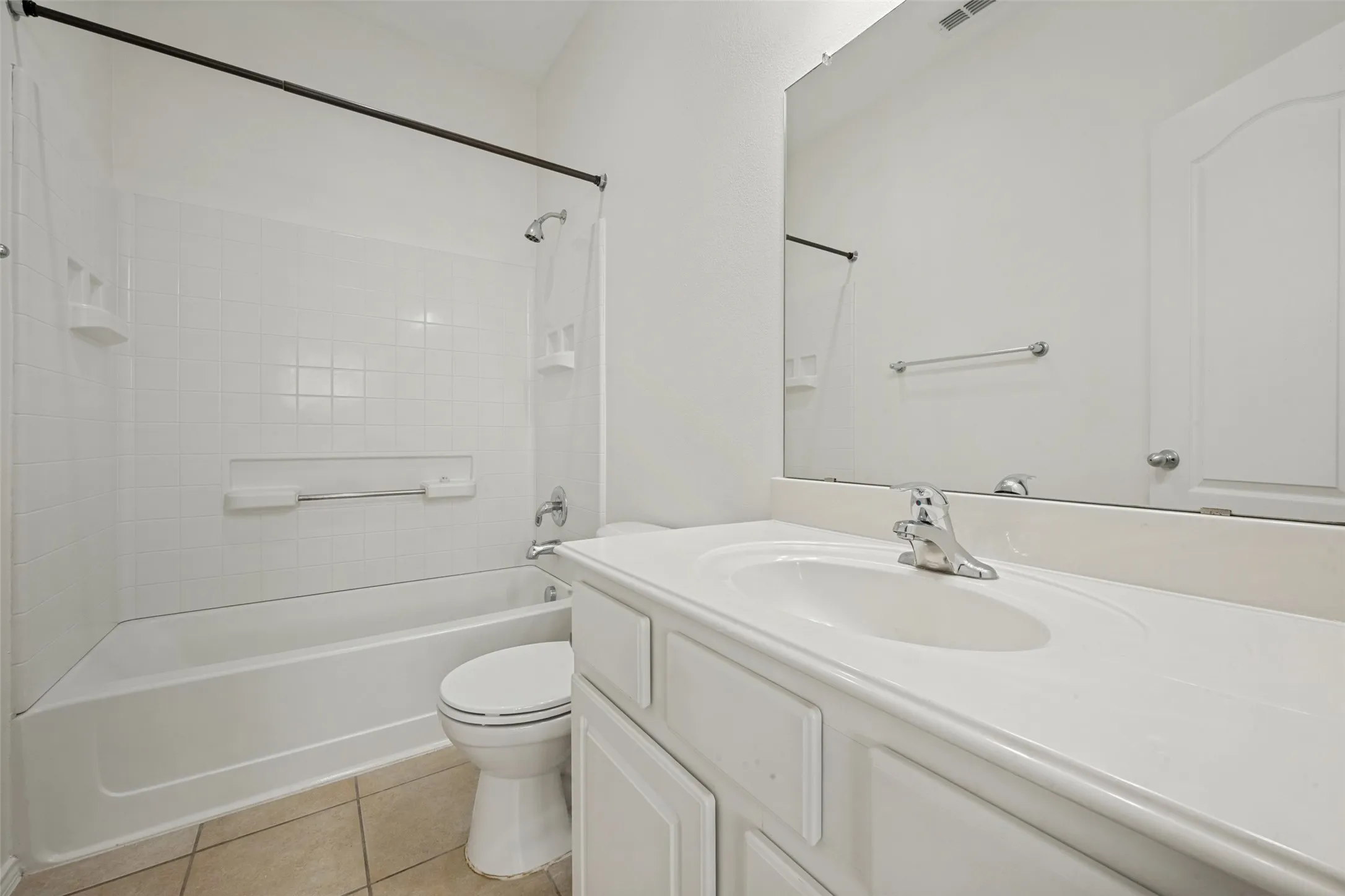 White vanity with integrated sink, chrome faucet, and expansive wall-mounted mirror