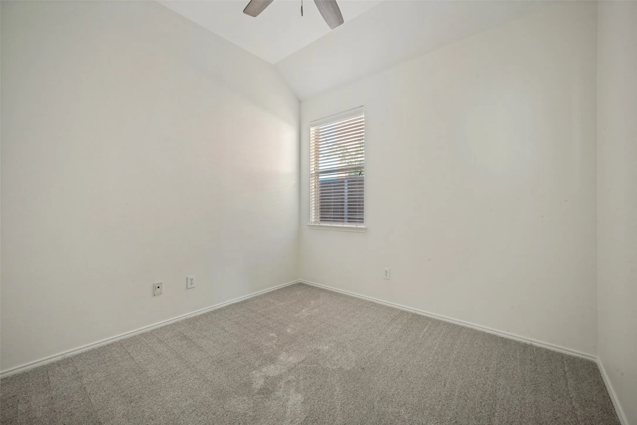 Vaulted ceiling, ceiling fan, neutral wall paint, carpet flooring, window with blinds