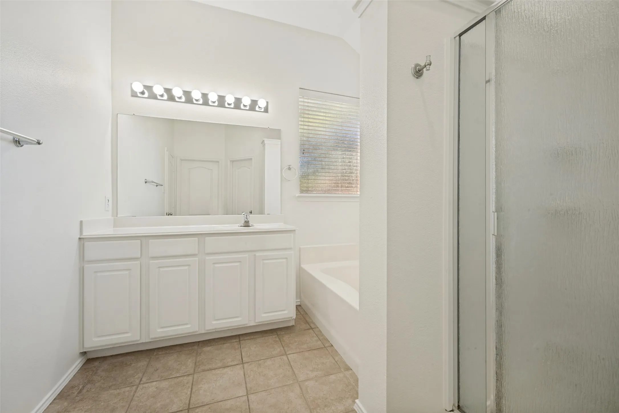 White vanity with integrated sink, large mirror, and overhead strip lighting