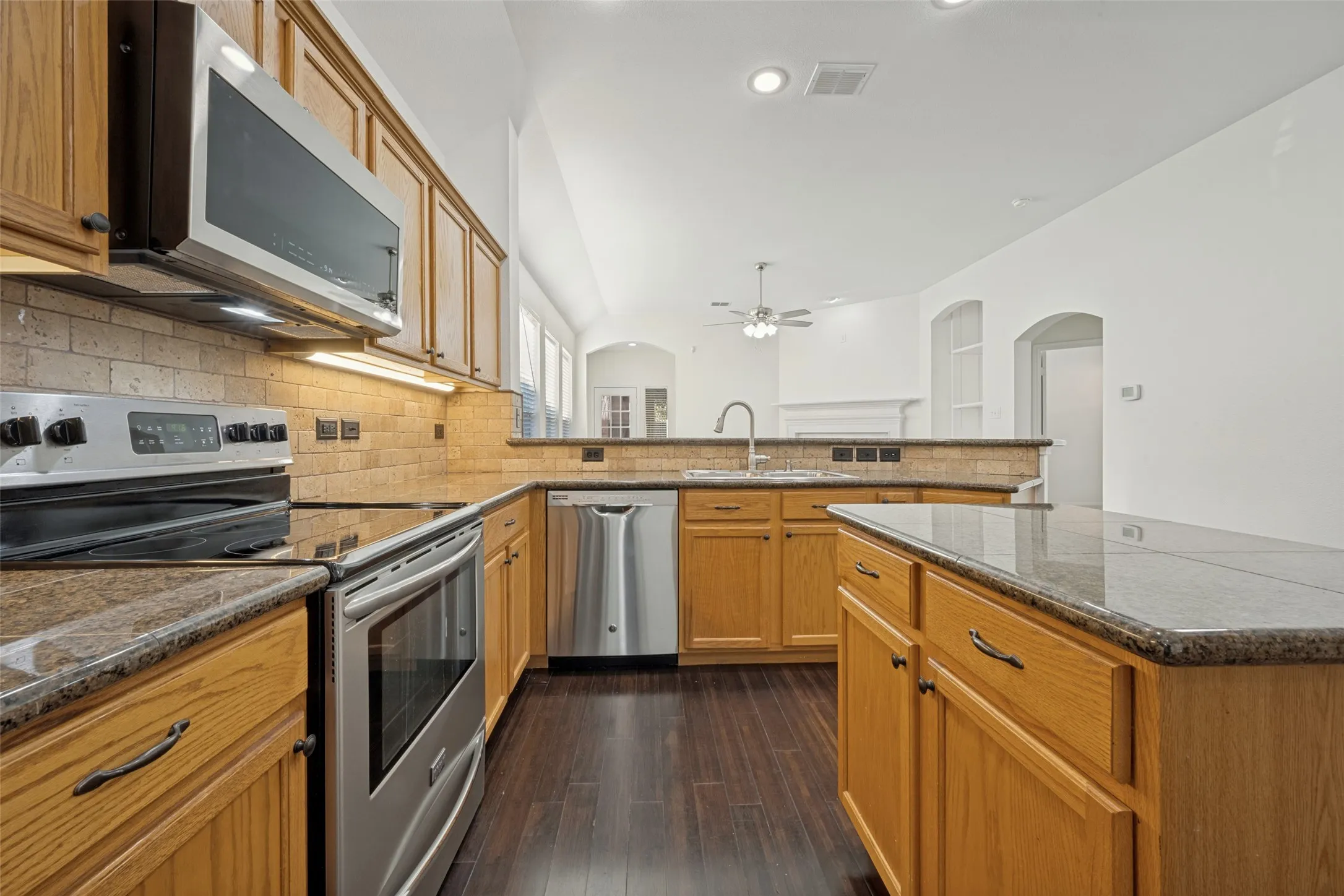 Kitchen featuring wood-finish cabinetry, stainless steel appliances, granite countertops, and a tile backsplash