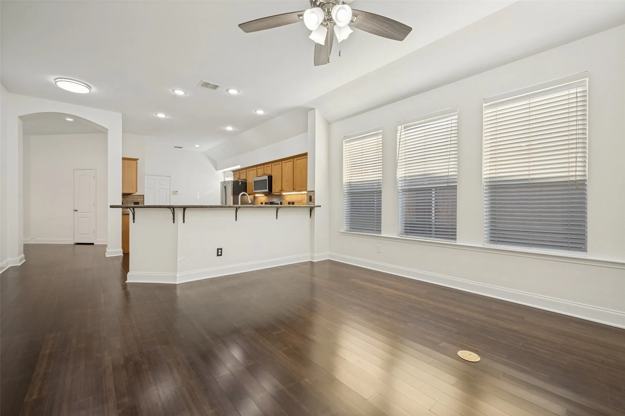 Open-concept living space with dark wood-finish flooring, recessed lighting, and a ceiling fan