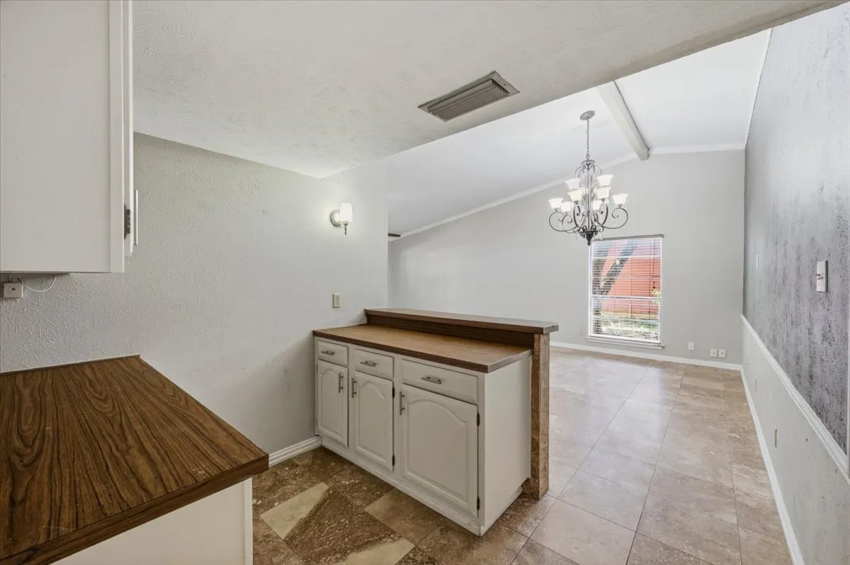 Dining Area features the butlers pantry's wood countertop and a wall sconce light fixture. Tile flooring extends throughout.