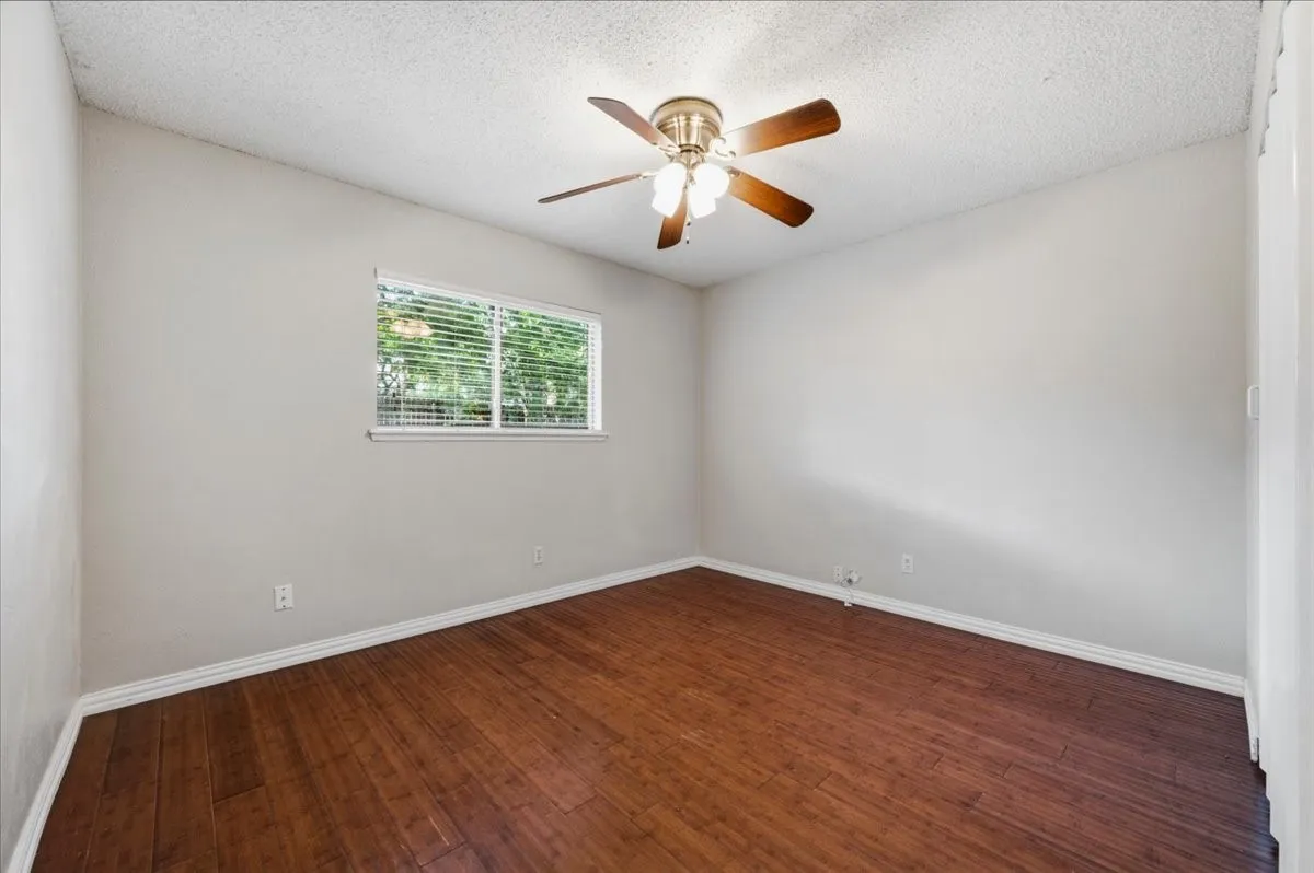Secondary Bedroom features ceiling fan with light fixture and a bifold closet door. Wood flooring extends throughout.