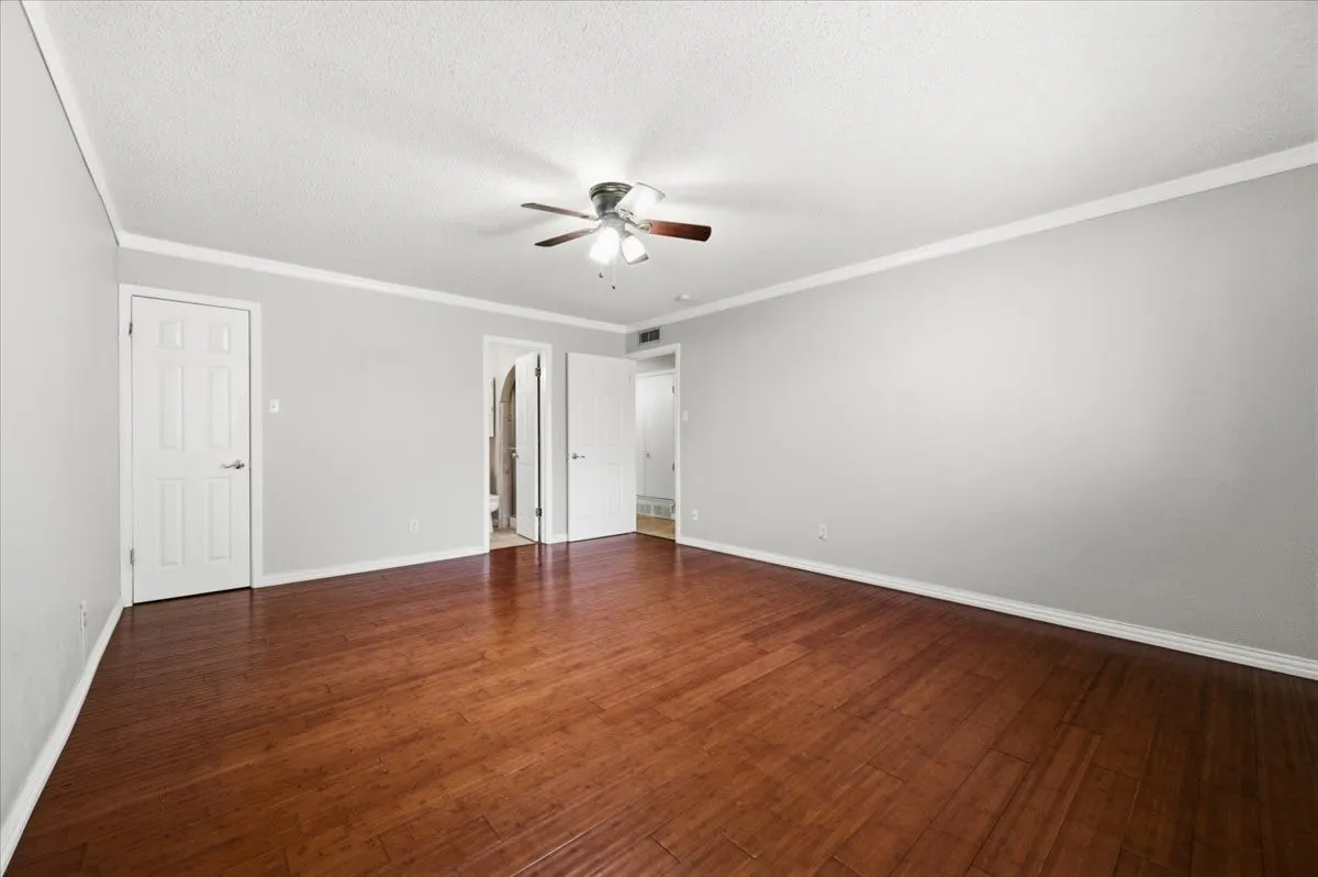 Primary Bedroom features crown molding, with doors opening to the ensuite bath and walk-in closet. Wood flooring extends throughout.