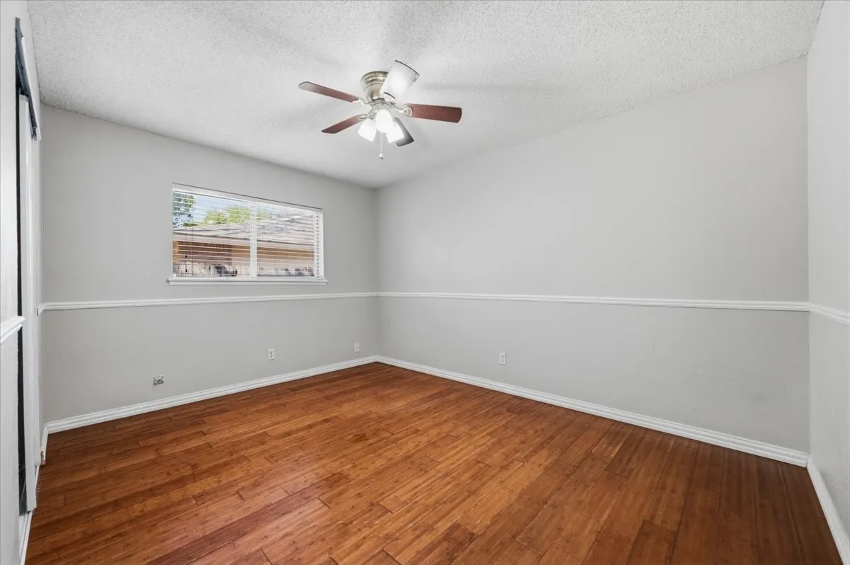 Secondary Bedroom features ceiling fan with light fixture, a two-tone wall treatment with chair rail, and a single window. Wood flooring extends throughout.