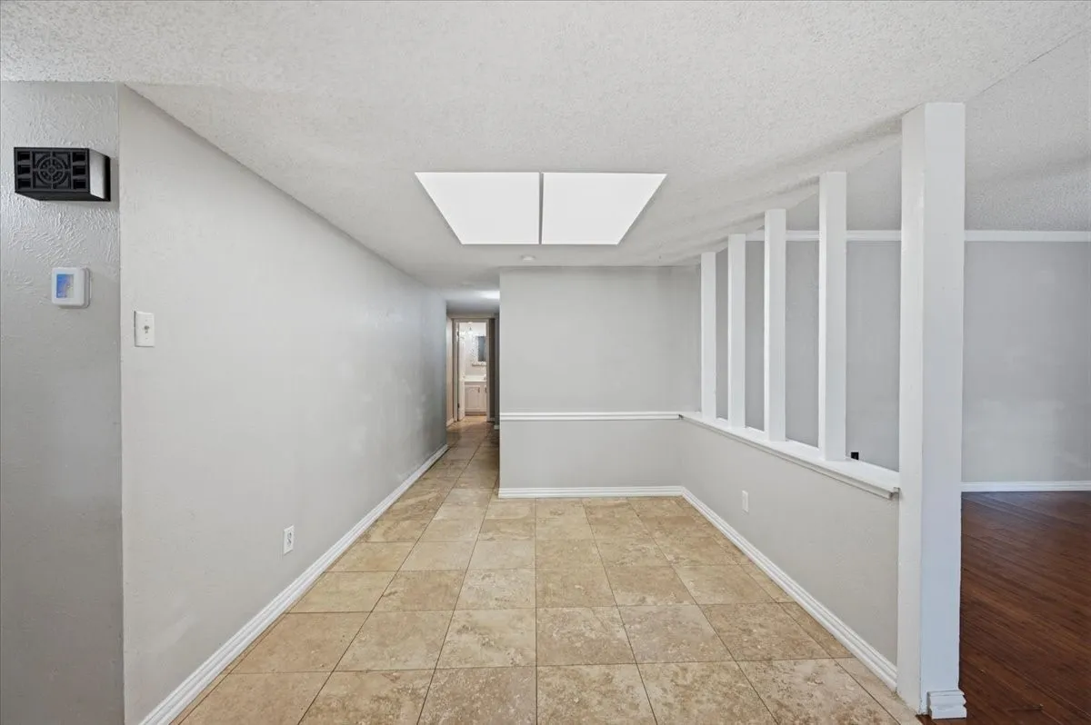 Breakfast Room/Nook features the same overhead lighting from another angle, with the spindle half-wall visible alongside a hallway leading toward a bathroom. Tile flooring extends throughout.