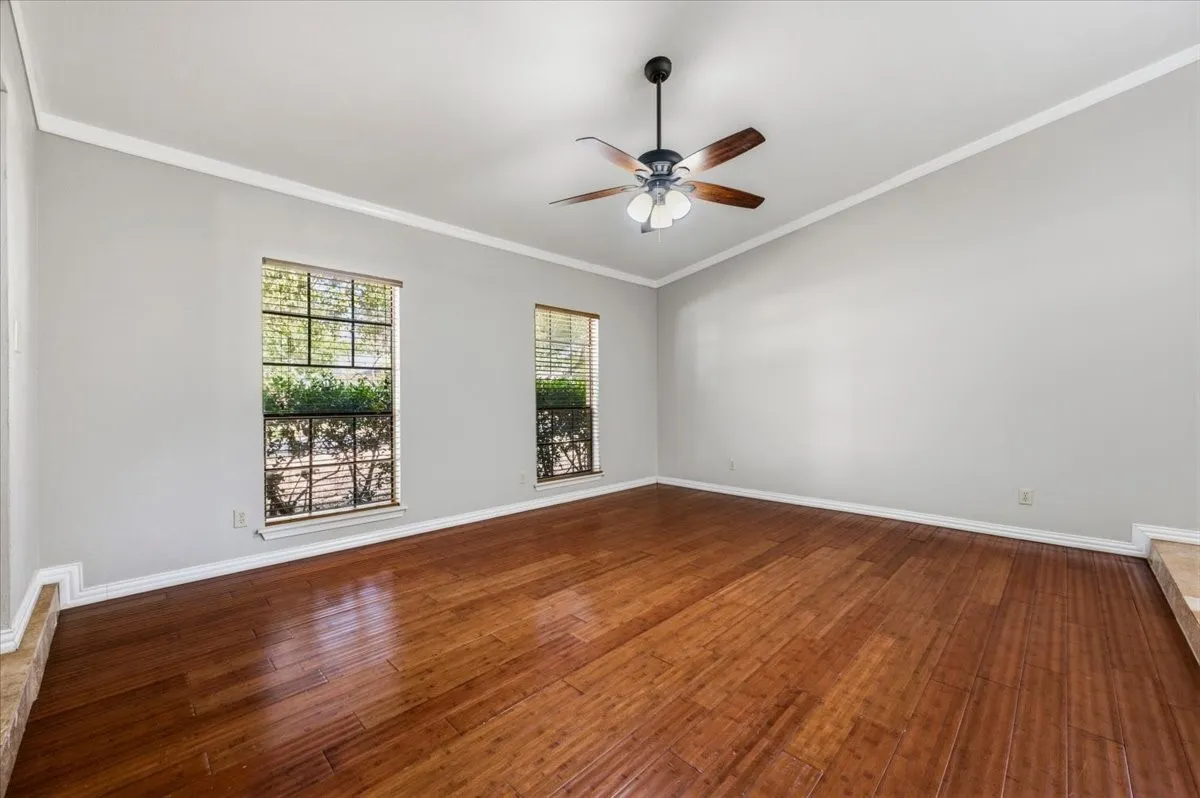 Living Room features crown molding and ceiling fan with light fixture, with two windows framing the space. Wood flooring extends throughout.