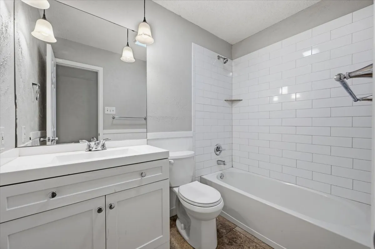Full Bathroom features a single vanity with pendant light fixtures, alongside a tub/shower combo with subway tile surround. Tile flooring extends throughout.