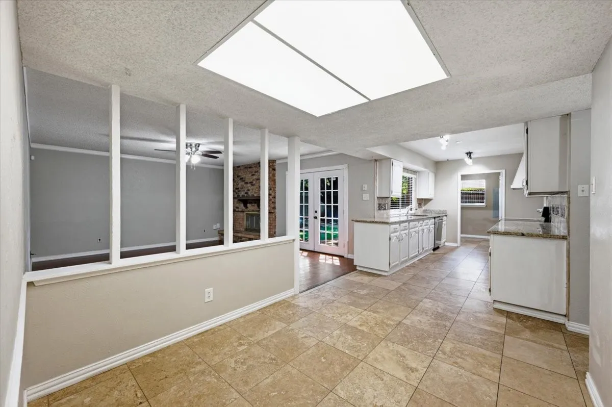 Breakfast Room/Nook features overhead lighting, with a decorative half-wall and spindle detail separating the space from the adjoining family room. The area opens directly to the kitchen. Tile flooring extends throughout.