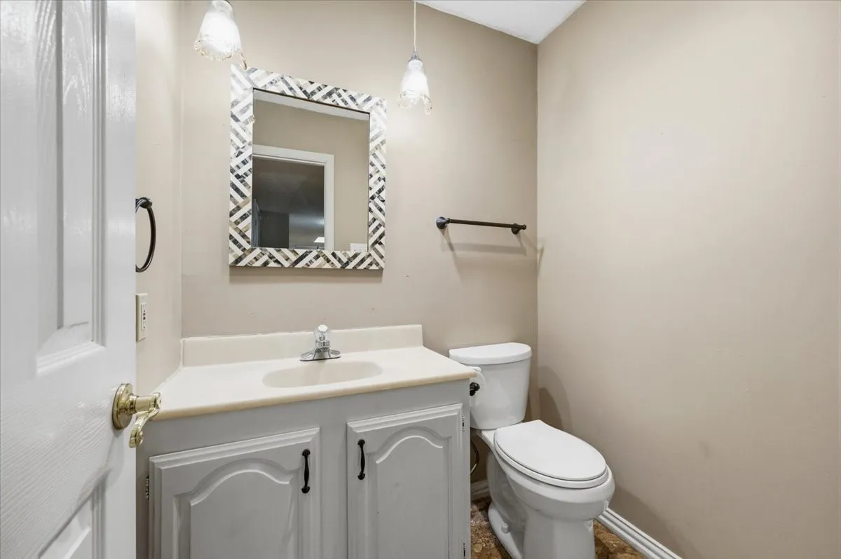 Half Bathroom features a single vanity with a decorative mirror and pendant light fixtures, with a towel bar mounted nearby. Tile flooring extends throughout.
