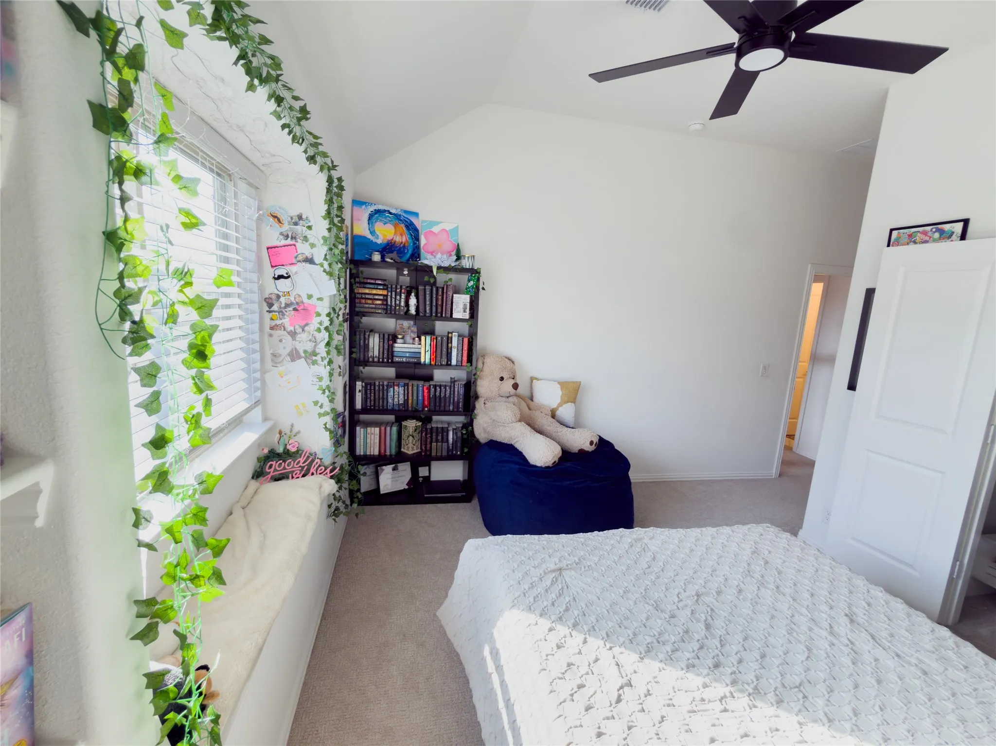 Bedroom featuring light carpet, vaulted ceiling, and a ceiling fan