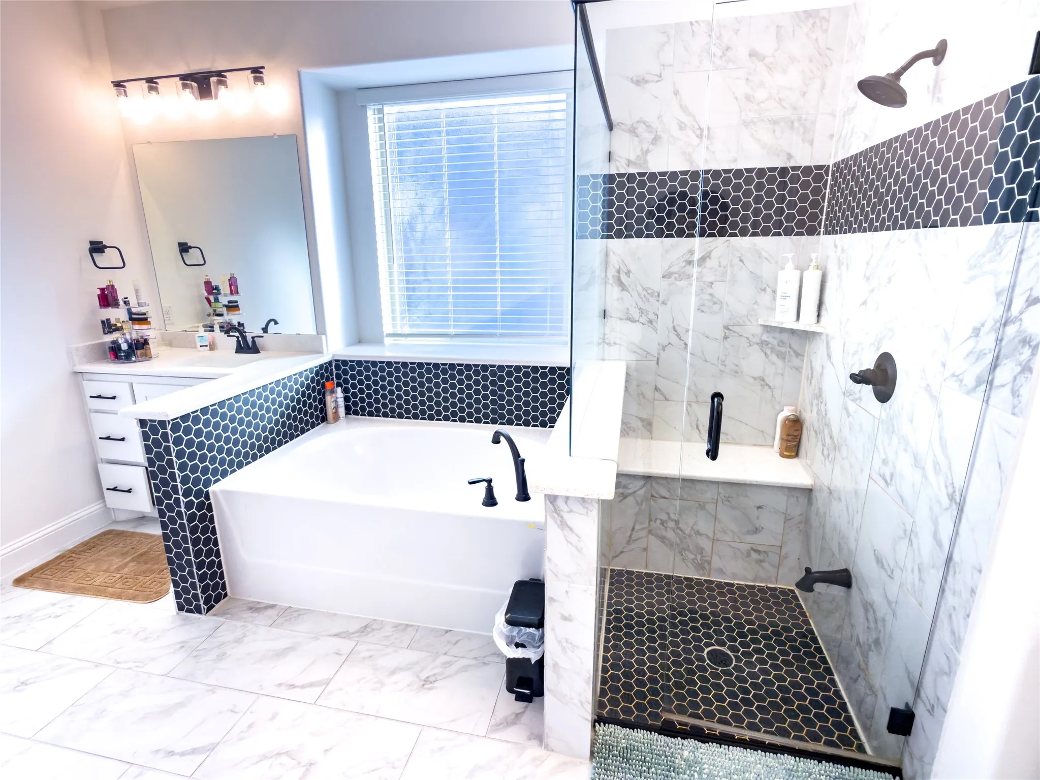 Full bath featuring a marble finish shower, a garden tub, vanity, light marble finish flooring, and pet washing station