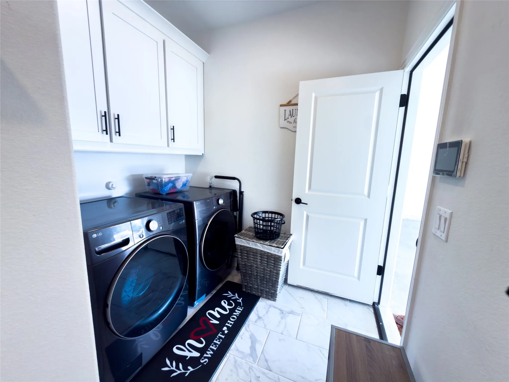 Laundry area with cabinet space, light marble finish flooring, and washing machine and clothes dryer