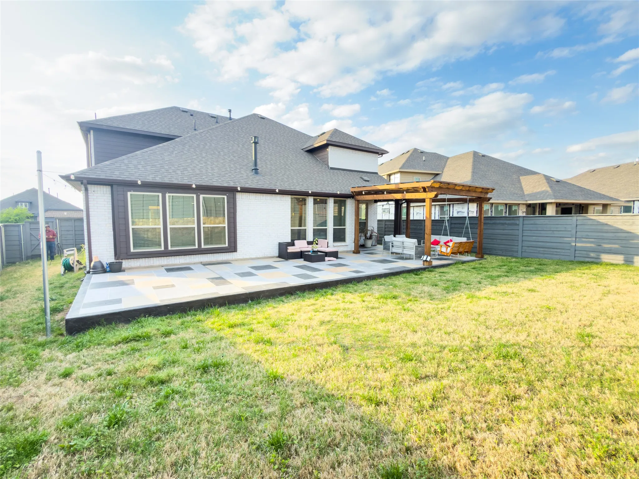 Rear view of house featuring a patio, an outdoor lounge area, a fenced backyard, roof with shingles, and brick siding