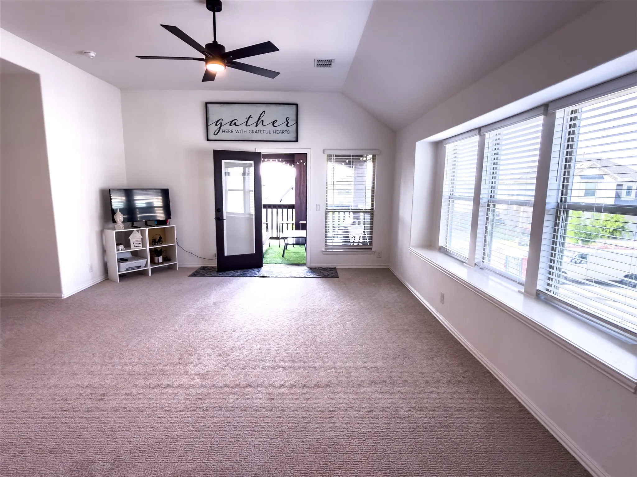 Empty room featuring a ceiling fan, vaulted ceiling, and carpet floors