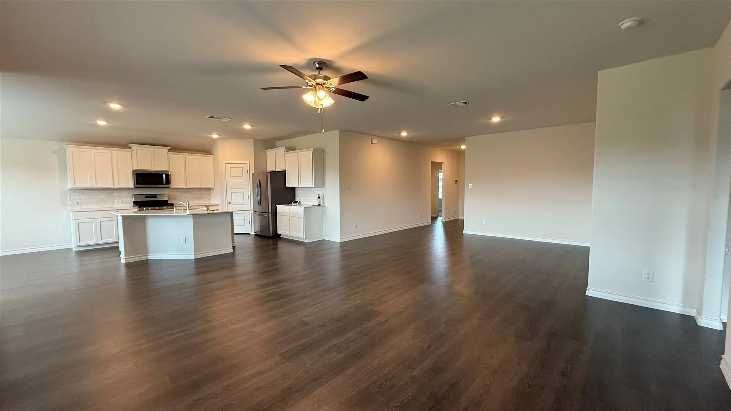 Open-concept living area featuring wood-finish flooring, recessed lighting, and a ceiling fan