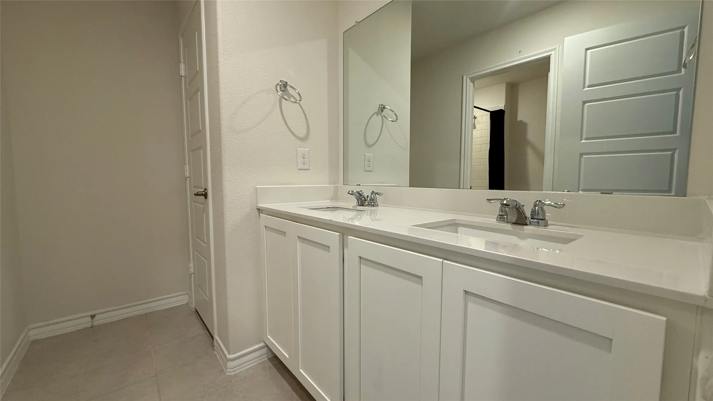 Dual vanity with white cabinetry, rectangular undermount sinks, and a single wall-mounted mirror