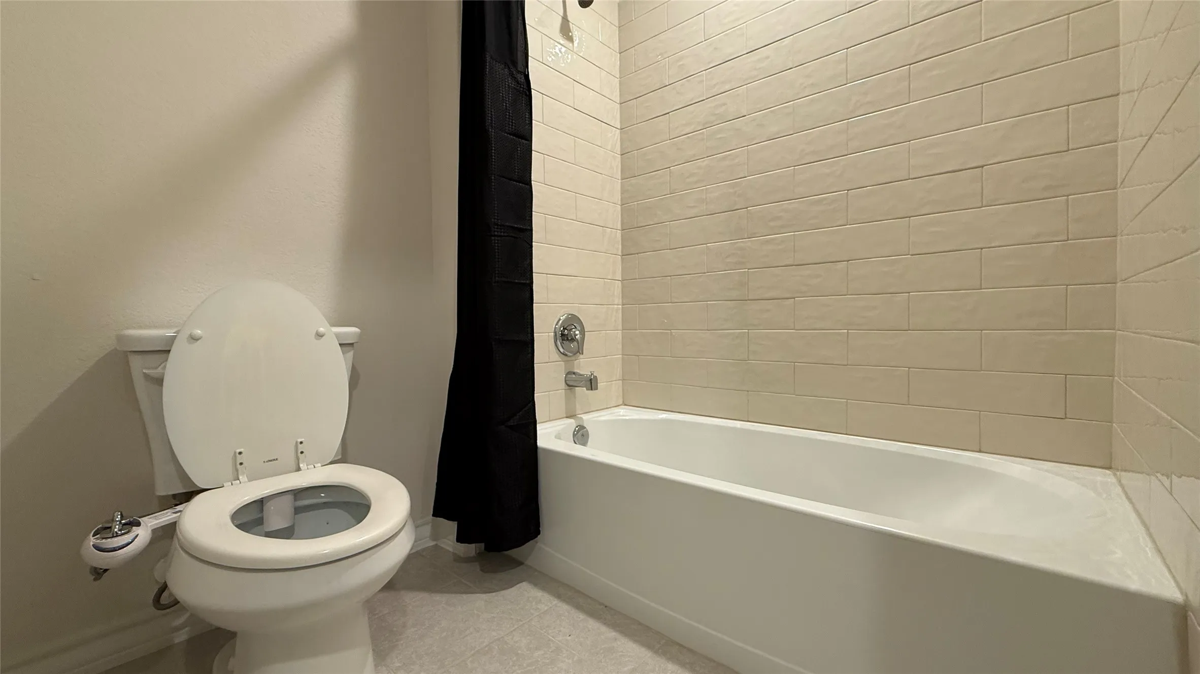 Bathroom featuring a white bathtub, subway tile shower surround, and a toilet with an attached bidet