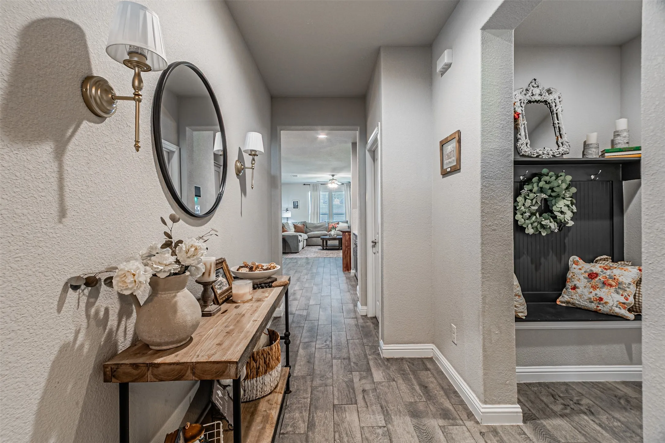 Hallway featuring wood-finish flooring, built-in shelving, and wall sconce lighting