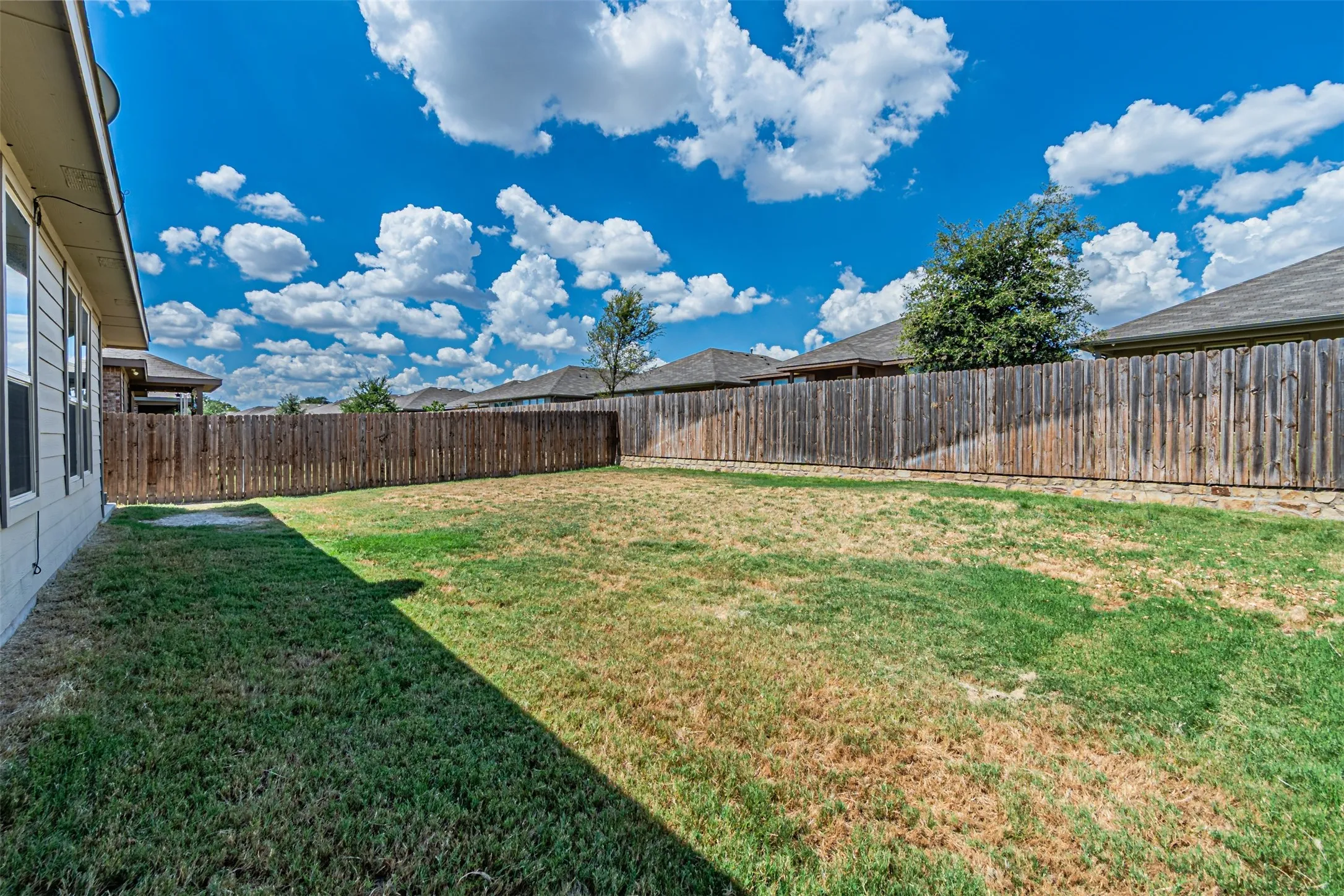 Expansive backyard with a wood privacy fence and a manicured lawn