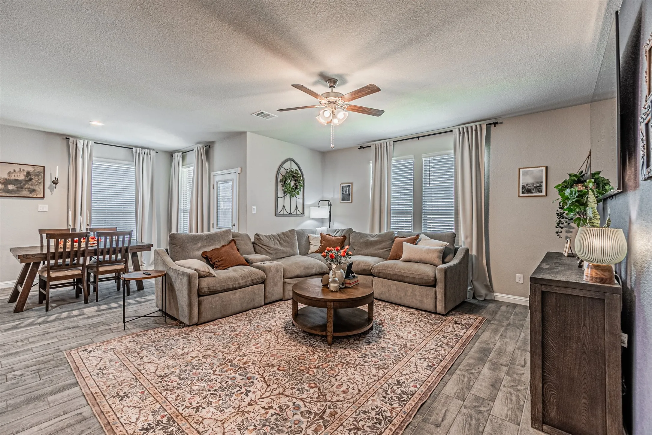 Recessed lighting throughout, wood-finish flooring, ceiling fan, multiple windows with blinds, and a built-in console