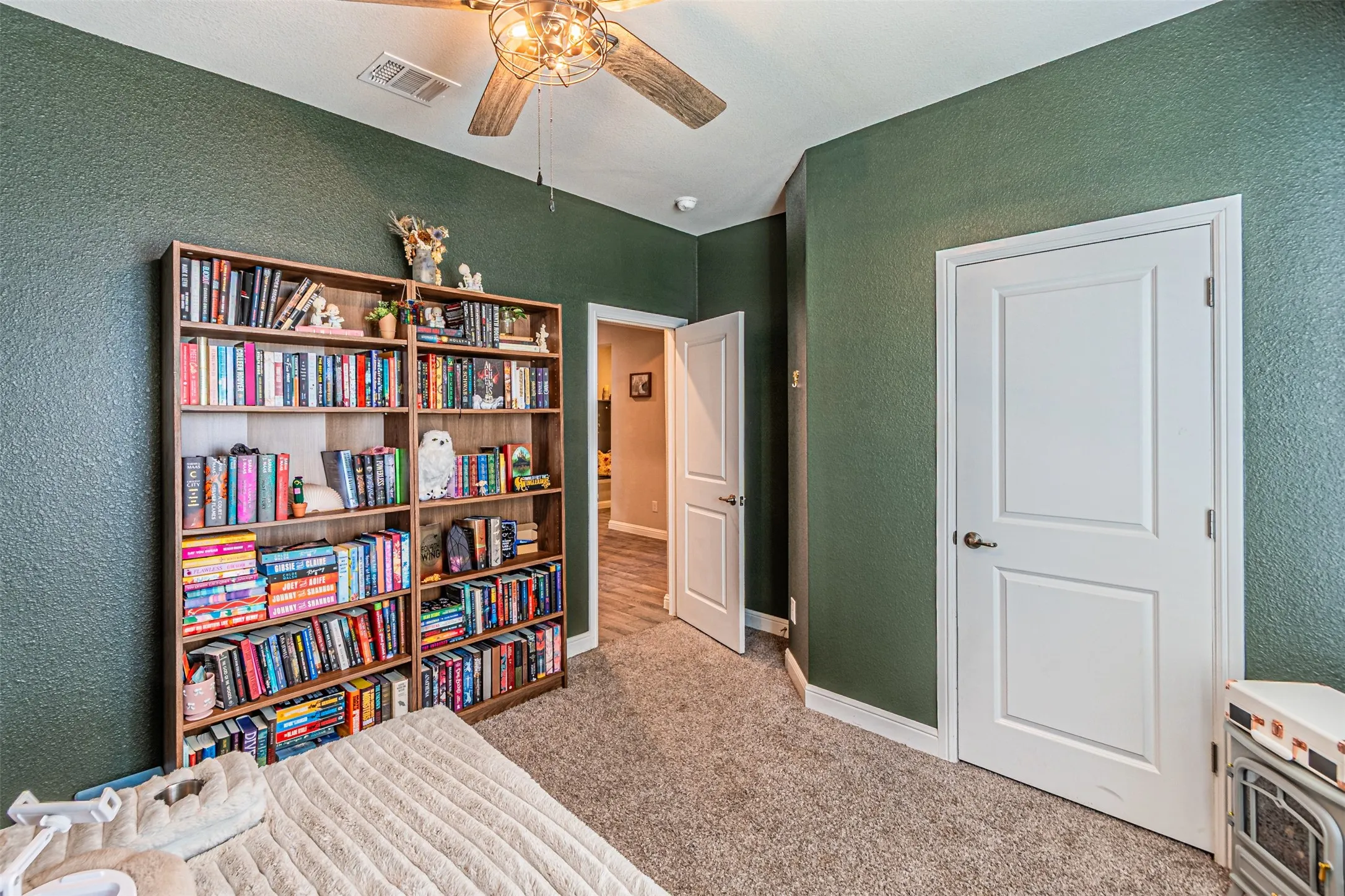Textured green wall finish, ceiling fan, white panel doors, and carpet flooring