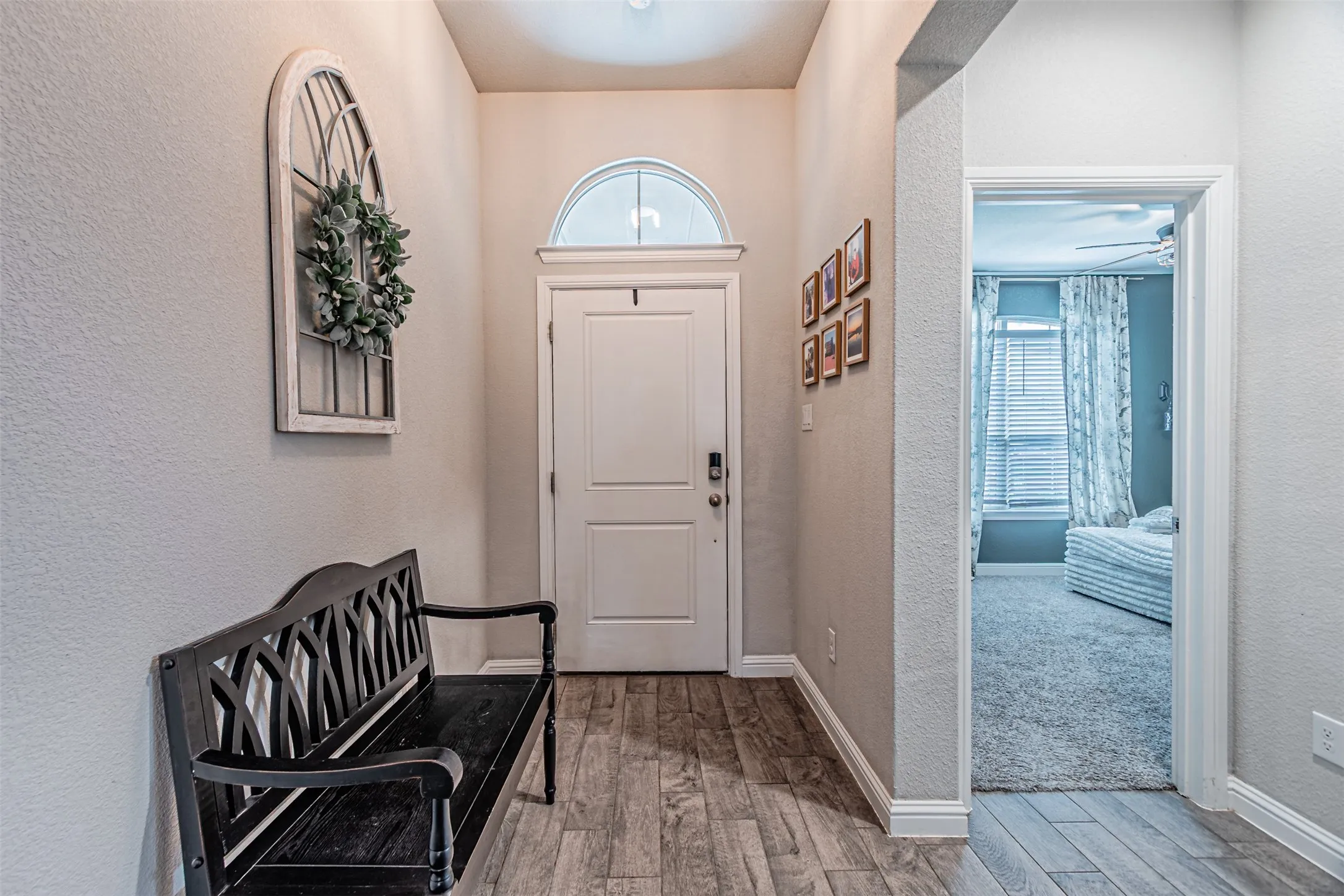 Foyer featuring wood-finish flooring, a paneled entry door with an arched transom, and light neutral wall tones