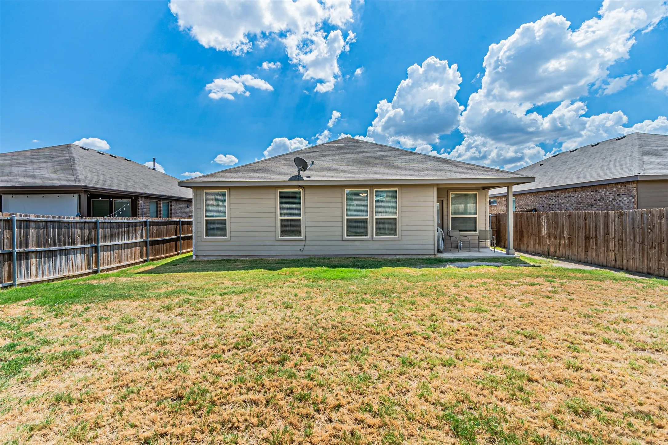 Rear exterior with covered patio, wood fencing, and multiple windows