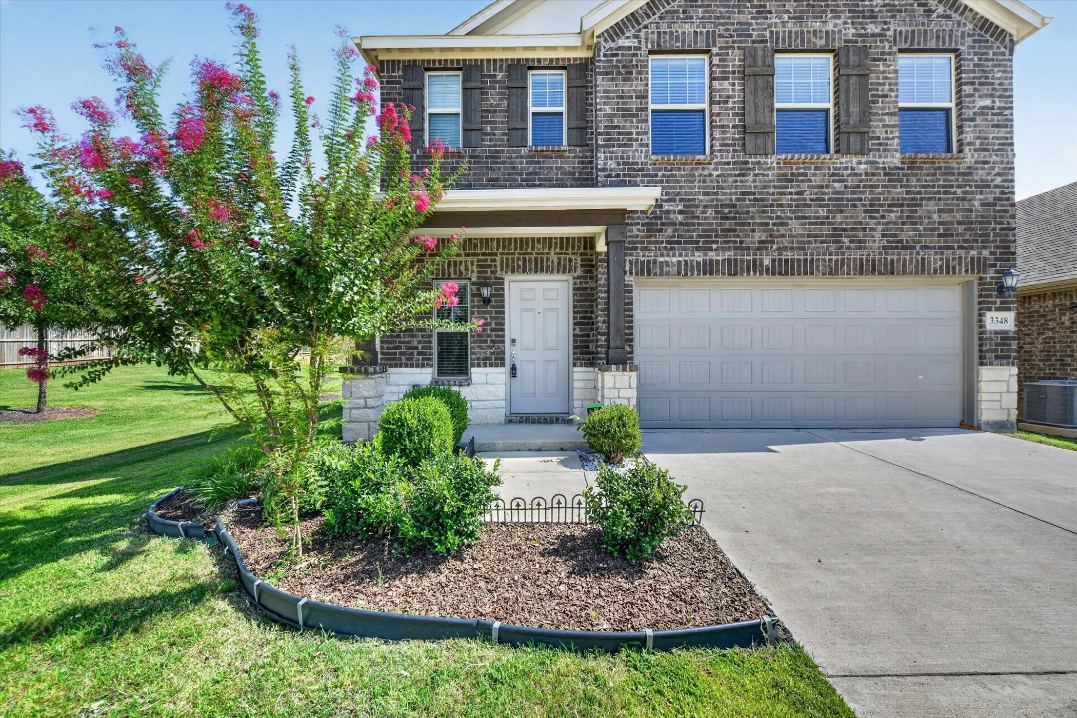 Brick exterior with stone accents, covered entry, and attached garage